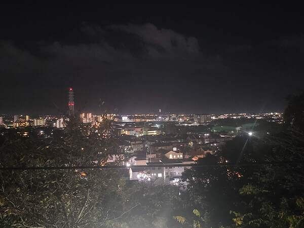 Cityscape at night looking out over Fujisawa and towards the coast. Houses and streetlights flood the photo with light